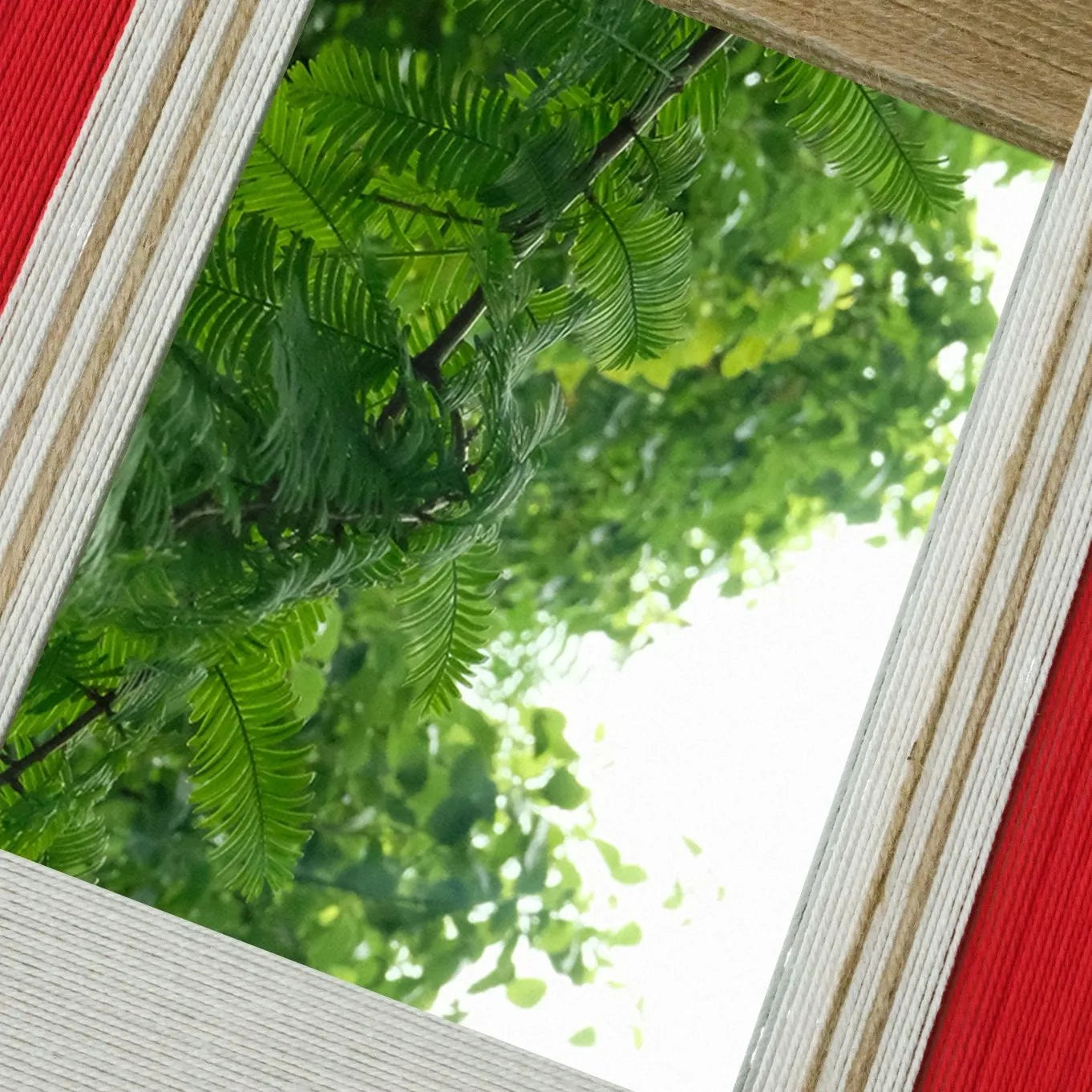 Close-angled view of The Sun Always Rises yarn mirror art highlighting tight looped wool texture on stripe borders and the reflective center catching natural light.
