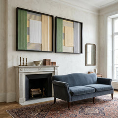 A pair of framed Sun-Baked hand-woven textile arts displayed as a focal point above a white fireplace mantel in a room with a stylish dark blue sofa.
