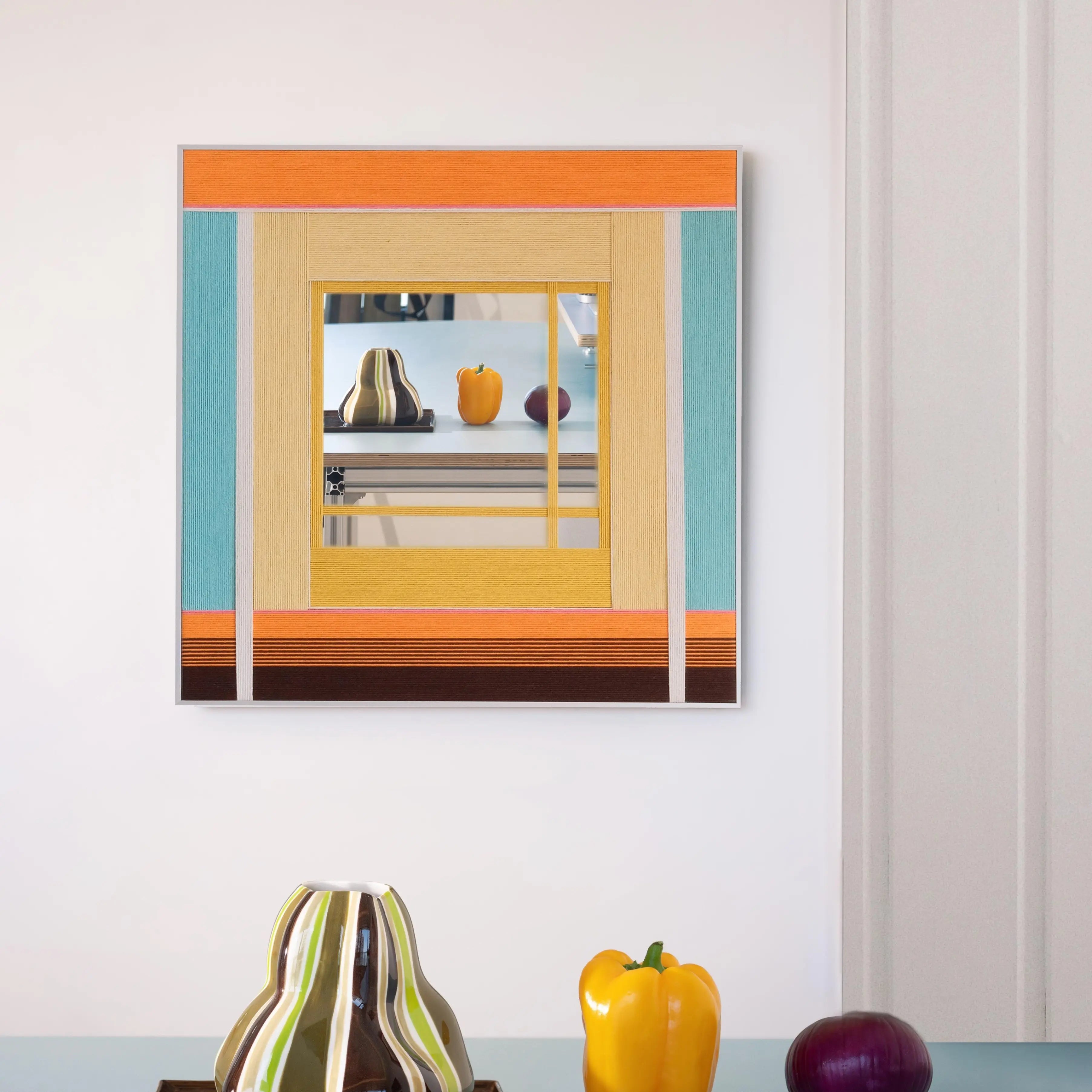 Sun‑Drenched Days yarn wall art styled on a desk beside notebooks and a ceramic cup, showcasing its soft stripe palette and clean frame.
