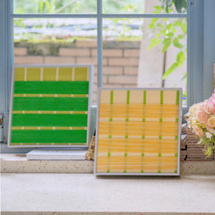 Textured fiber wall art frames displayed on a sunny window sill, bringing the fresh colors of spring indoors with green and yellow wool.