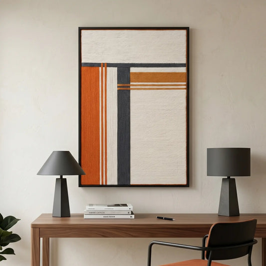 Framed textured fiber wall art hanging above a dark wood desk in a sophisticated home office with modern black lamps.