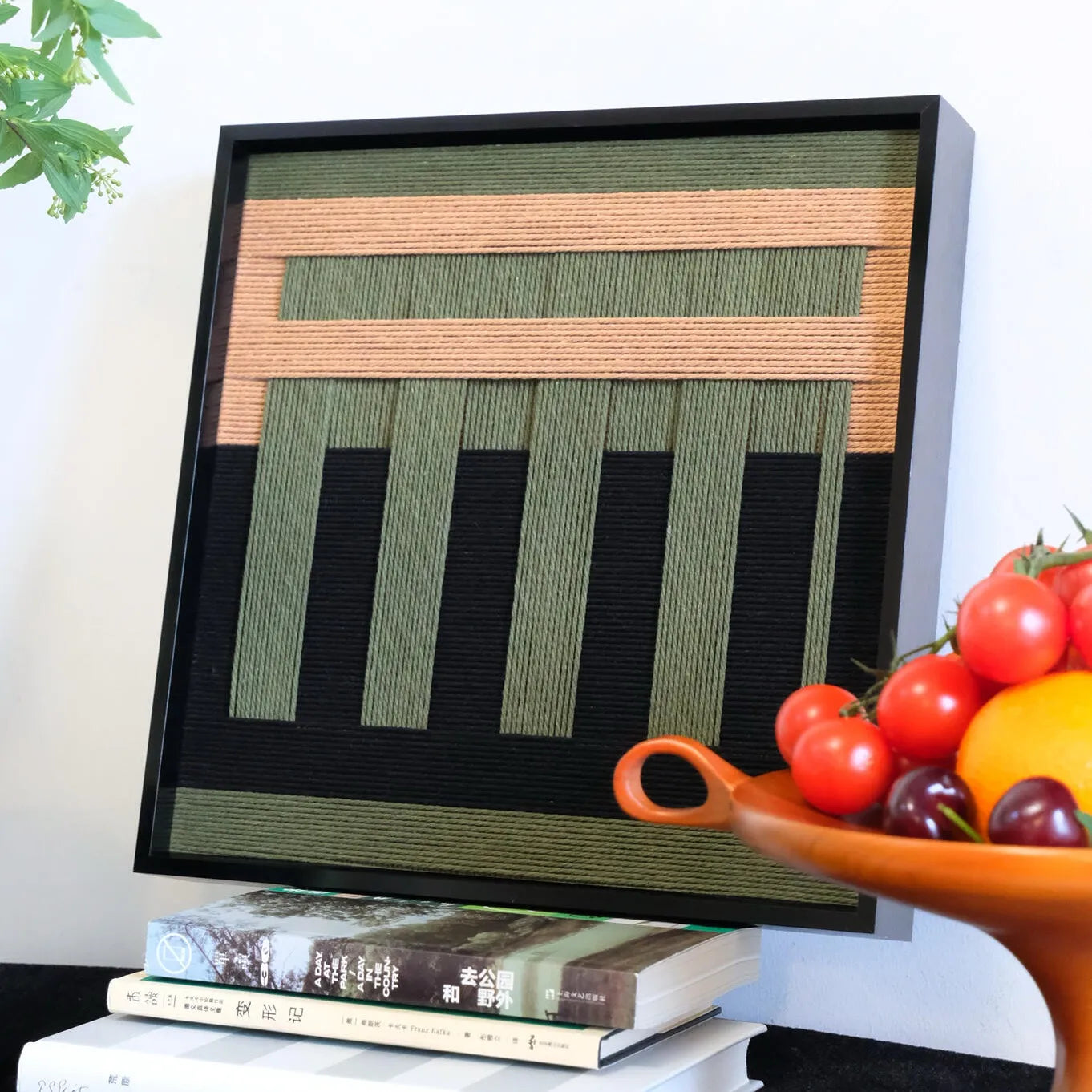 Close-up view of the textured wool wall hanging, highlighting the relief of the green vertical stripes against a black background.