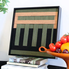 Close-up view of the textured wool wall hanging, highlighting the relief of the green vertical stripes against a black background.