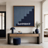 The Eighth Level blue stepped textile wall art styled above a modern wood desk in a calm minimalist entryway.