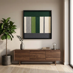 Framed fiber art tapestry with a modern geometric design displayed in a bright living room above a dark walnut sideboard.