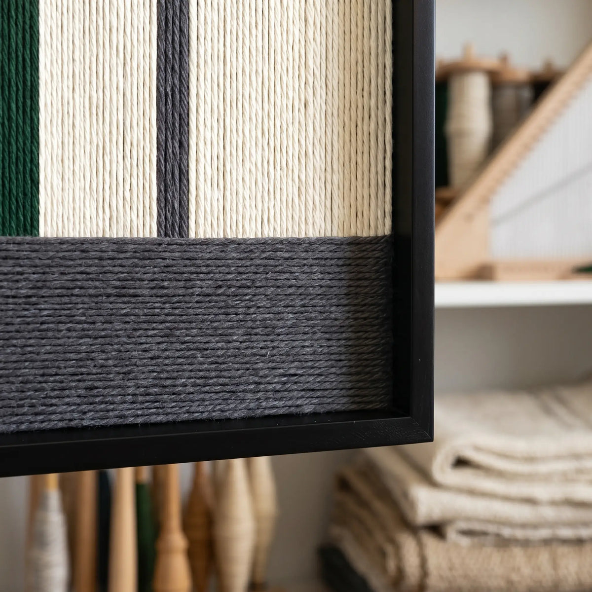 Close-up craftsmanship detail of The Interval textile wall art showing tightly wrapped forest green, cream, and charcoal yarn within a black frame.