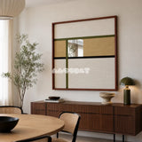 Through the Mirror cream, tan, olive, and black yarn-framed mirror displayed above a walnut sideboard in a modern dining room.
