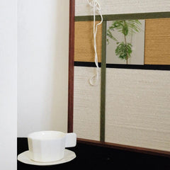 Tabletop close‑up of Through the Mirror showing tight looped wool stitches and seamless transitions between cream and olive stripe panels.
