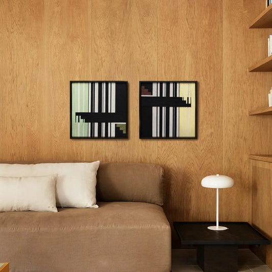 Timeless Moments diptych hung above a couch in a modern living room, showcasing its balanced grid of green, ivory, and black yarn stripes.

