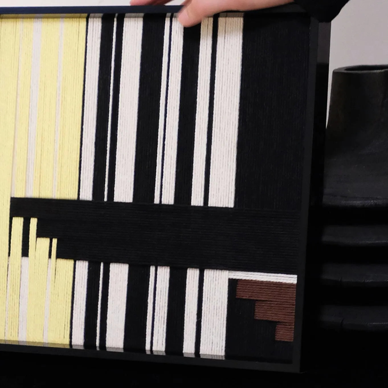 Close-up of Timeless Moments yarn wall art revealing tight looped wool texture and crisp transitions between green, ivory, and black stripes.
