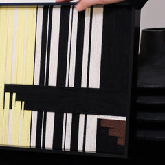 Close-up of Timeless Moments yarn wall art revealing tight looped wool texture and crisp transitions between green, ivory, and black stripes.

