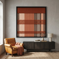 Large square Tuscan Plaid hand-woven wall art hanging elegantly above a sleek black sideboard next to a tan leather armchair in a modern living room.