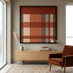 Framed Tuscan Plaid textile wall art displayed in a bright living room, hanging above a light wooden credenza next to a brown leather lounge chair.