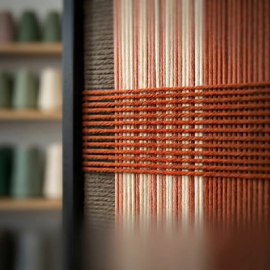 Extreme angled macro close-up of the Tuscan Plaid hand-woven textile art highlighting the textured terracotta horizontal yarn crossing over brown and rust vertical stripes.