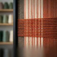 Extreme angled macro close-up of the Tuscan Plaid hand-woven textile art highlighting the textured terracotta horizontal yarn crossing over brown and rust vertical stripes.