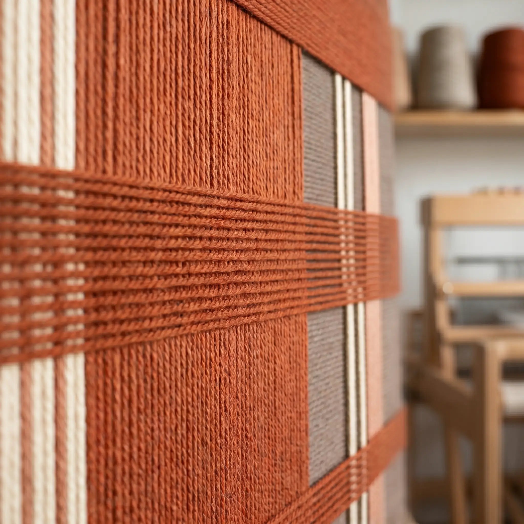 Extreme low-angle macro shot of the Tuscan Plaid hand-woven textile art lying flat, highlighting the raised, dimensional terracotta and brown yarn texture.