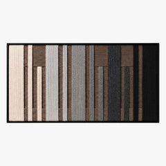 Frontal studio shot of the Umber Columns hand-woven wool wall art featuring vertical grey, brown, black, and cream stripes in a black frame.