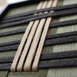 Angled close-up of the Verdant Silence framed wall art highlighting the dimensional black and cream woven wool yarn patterns.