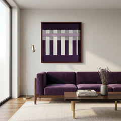 Modern hand-woven wool wall hanging styled above a sleek purple velvet sofa in a minimalist living room with neutral walls.