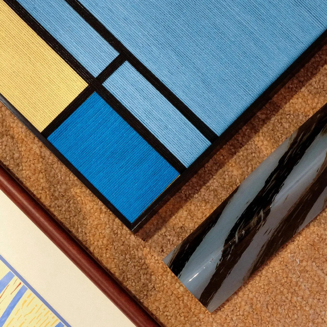 Macro close-up of Weave Reshape yarn wall art revealing looped wool texture and the precision of its grid pattern.
