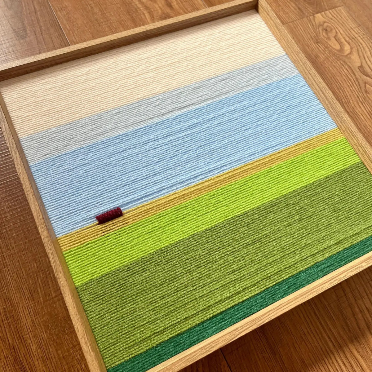 Close-up corner detail of Whispering Fields soft cotton cord fiber artwork showing textured blue and green fields.