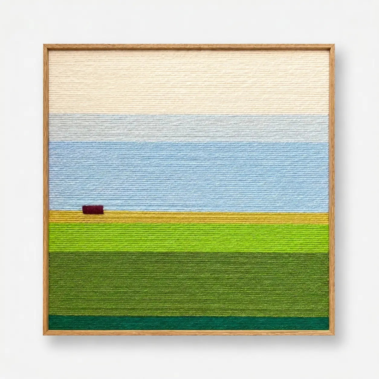 Full product view of the landscape hand-woven wool wall art framed neatly, showcasing cream sky and green fields.