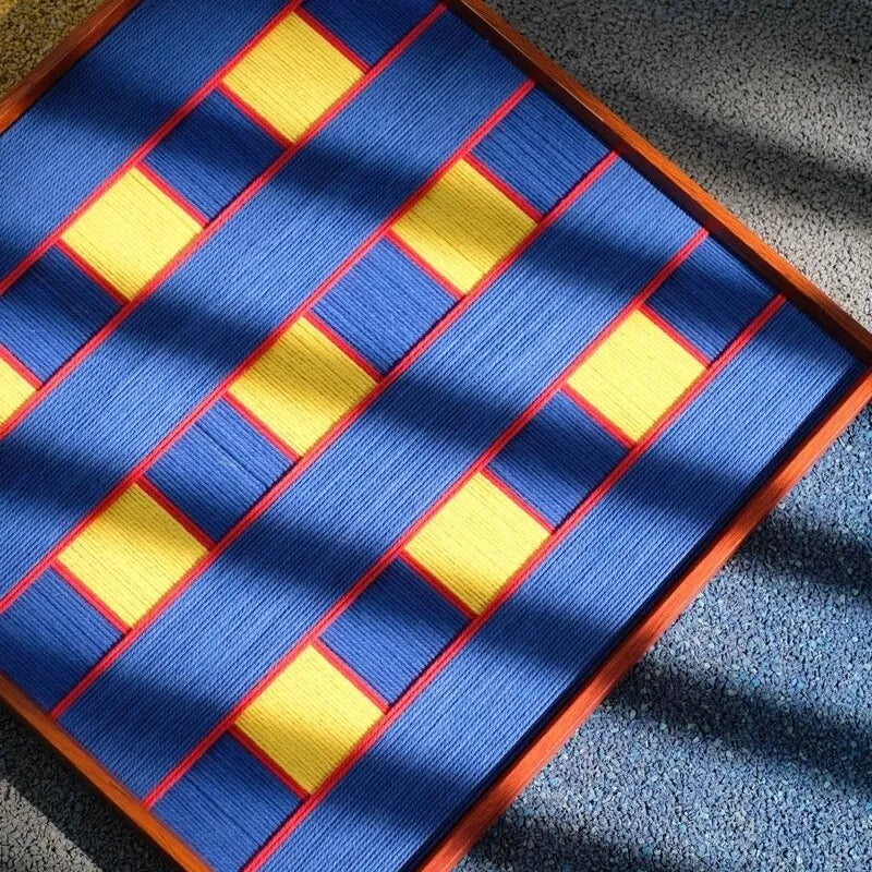 Close-up of Moonlit Windows fiber wall art showing royal blue yarn, yellow blocks and red borders