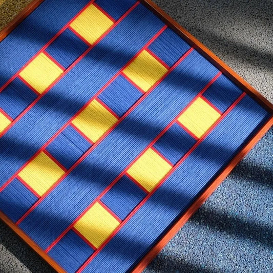 Close-up of Moonlit Windows fiber wall art showing royal blue yarn, yellow blocks and red borders