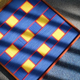 Close-up of Moonlit Windows fiber wall art showing royal blue yarn, yellow blocks and red borders
