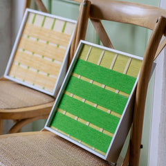 The Spring Breeze fiber art set resting on a wooden chair, highlighting the natural textures of the wool against rustic furniture.